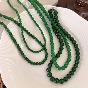 Elegant multi-layered emerald green beaded necklace set with silver yuanbao clasp on ceramic