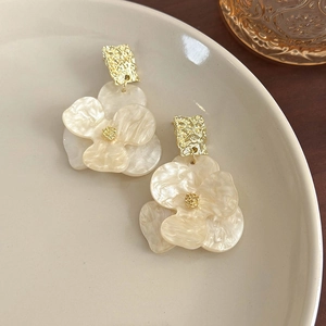 Detail of flower earrings with gold hammered texture and pearlescent resin petals