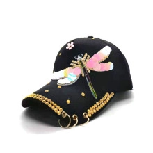 Detailed close-up of sequined dragonfly and cherry blossom on a black baseball cap