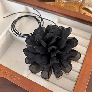 Close-up of a handmade black chiffon flower necklace in a premium wooden jewelry box