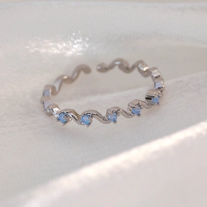 Detailed close-up of wavy silver adjustable ring with five light blue round gemstones
