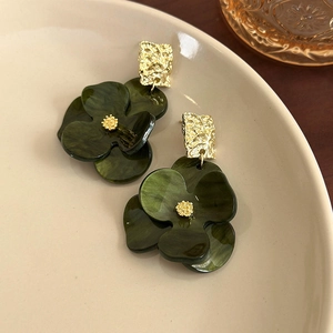 Detail of vintage French floral earrings with dark green petals and golden metal texture