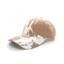 Detail view of khaki cotton baseball cap with white graffiti splatter pattern details