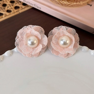 Close-up of pink lace flower earrings with white pearl center on a ceramic plate