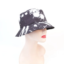 Detail of black street style bucket hat with white splatter ink print and M logo