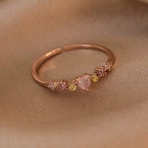 Close-up of rose gold open ring featuring a pink heart stone and multi-colored zircons