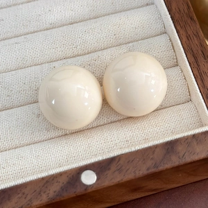 Dettaglio macro di orecchini a perla bianca su un vassoio espositore in legno pregiato
