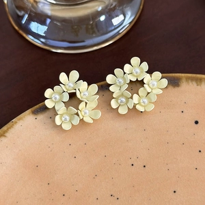 Dettaglio di orecchini a cerchio con fiori gialli e perle bianche su ceramica