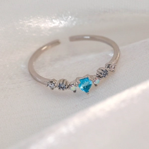 Macro detail of silver adjustable ring featuring a heart-shaped blue zircon and crystals