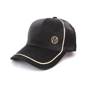 Detail of black satin baseball cap featuring gold piping and metallic M logo accent