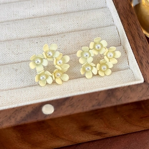Dettaglio ravvicinato di orecchini a fiore con perle color crema in una scatola di legno