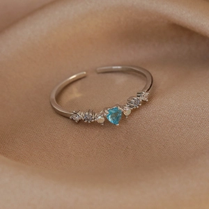 Detailed macro shot of adjustable silver ring with heart-shaped sea blue gemstone