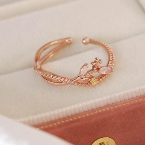 Detail of rose gold open ring with marquise-cut pink zircon leaves and tiny metal flower