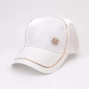 Detail of white satin baseball cap featuring a golden M logo and metallic piping accents