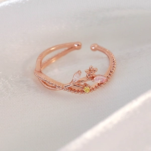 Detailed close-up of rose gold flower ring with colorful zircons on white silk