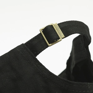 Detail of adjustable cotton strap with vintage metal buckle on black baseball cap