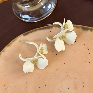 Vista dettagliata degli orecchini a fiore bianco con stami dorati su vassoio di ceramica