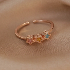 Detail of rose gold adjustable ring featuring three star-shaped colorful zircon accents