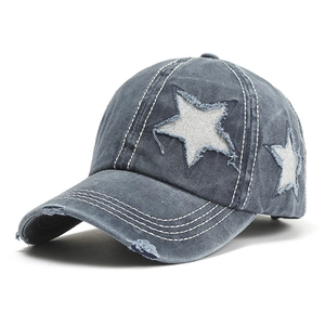 Detail view of washed denim baseball cap with distressed star patch and white stitching