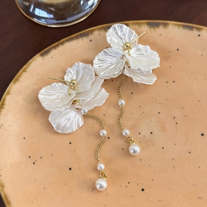Dettaglio di orecchini a nappa con petali di perla e catene d'oro su vassoio
