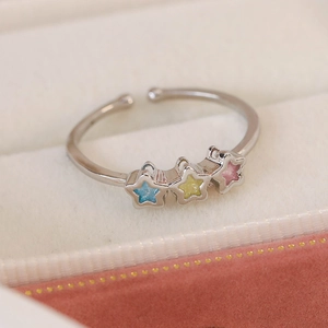 Close-up of adjustable silver ring with three pastel zircon stars on beige velvet