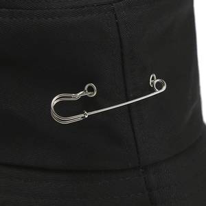 Detailed macro view of a black bucket hat with a silver metal safety pin decoration