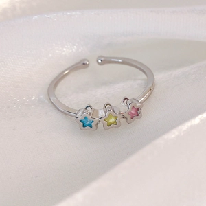 Detail of adjustable star ring with colorful stones on white silk background