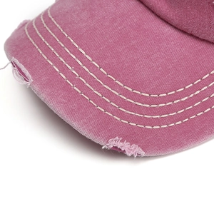 Pink washed canvas baseball cap with distressed hole detail and white stitched brim