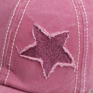Detailed macro view of a pink washed denim baseball cap with a purple glitter star patch