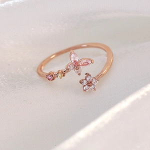 Macro shot of rose gold ring featuring pink zircon butterfly and floral micro-insets
