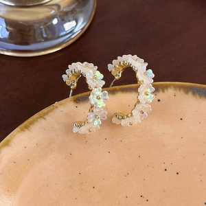 Dettaglio degli orecchini a fiori a forma di C con petali bianchi iridescenti e oro