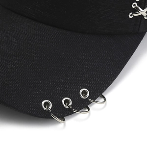 Dettaglio macro del cappellino nero in cotone con anelli d'argento e fibbie a croce