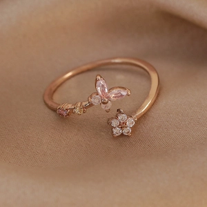 Macro detail of rose gold butterfly ring with pink zircon on champagne silk background