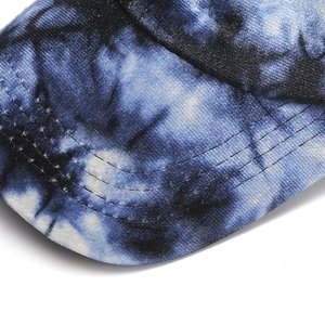 Detailed macro view of tie-dye velvet baseball cap brim with precise reinforced stitching