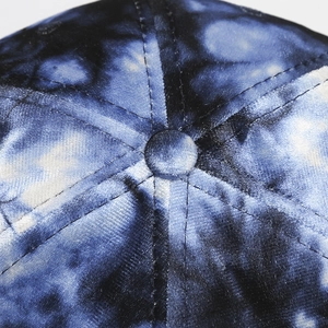 Detailed close-up showing tie-dye blue fabric textures and stitching of the baseball cap top
