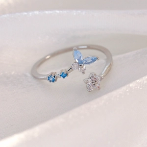 Macro shot of silver ring with blue butterfly zircons and star details on silk fabric