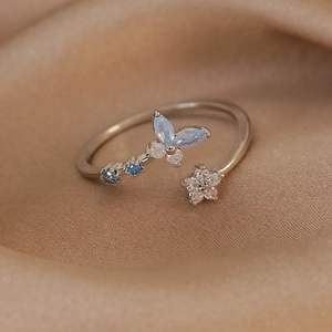 Macro shot of silver adjustable ring featuring a blue butterfly and zircon flower detail