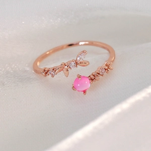 Macro detail of rose gold open ring featuring pink cat-eye stone and zirconia leaves