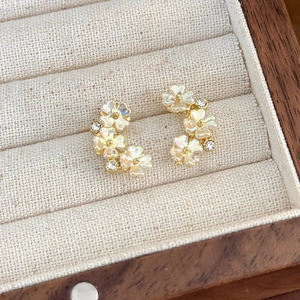 Dettaglio orecchini a fiore in madreperla con perle e cristalli su portagioie