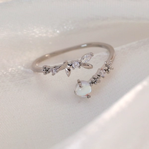 Macro detail of silver floral open ring with marquise zircons and moonstone on silk