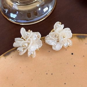 Dettaglio di orecchini a forma di fiore bianco con perle su ceramica stile vintage