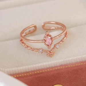 Macro detail of rose gold double-layer open ring with pink marquise stone and zircons