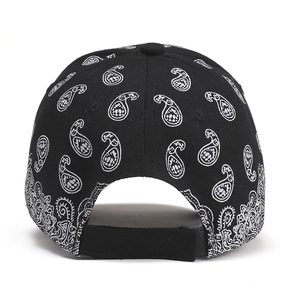 Detail view of black paisley baseball cap featuring white patterns and adjustable velcro strap