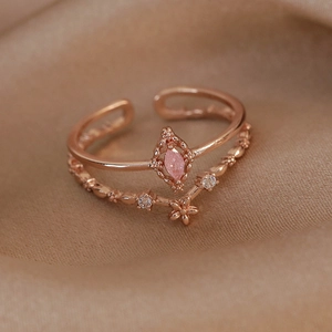 Macro shot of rose gold double-layer ring with pink marquise zircon on silk fabric