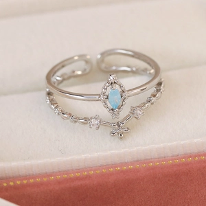 Detail of silver double-layered open ring with blue marquise stone and floral accent