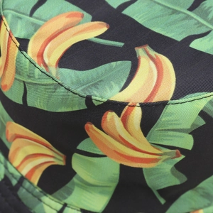 Close-up of tropical banana print and fine stitching on a black canvas bucket hat fabric