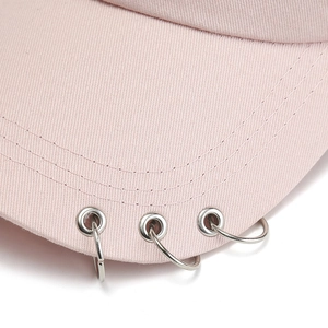 Detail of pink canvas baseball cap brim featuring three silver metal rings and stitching