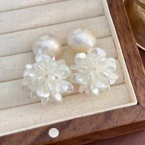 Dettaglio di orecchini di perle con petali di conchiglia traslucidi in un portagioie