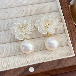 Dettaglio di orecchini a fiore di conchiglia con perle pendenti in una scatola di legno