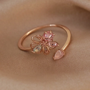 Macro detail of rose gold open ring with pink floral gems on champagne silk fabric